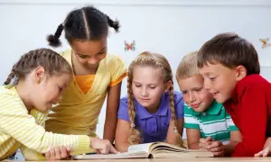 Pięcioro dzieci pochyla się nad otwartą książką, ucząc się, jak prowadzić zajęcia z dziećmi.