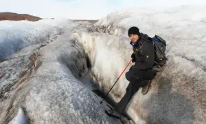 Mężczyzna na lodowcu w Europie, otoczony przez śnieg i lód, z kijkami trekkingowymi.