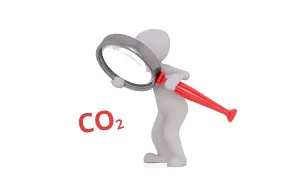 Biała figurka bada pod lupą, czy dwutlenek węgla (CO2) jest szkodliwy.