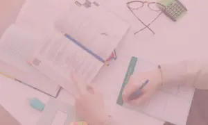 Uczeń pochyla się nad książką, notując w zeszycie. Czy oceny na studiach mają znaczenie?