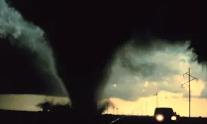 Potężny lejek tornado zbliża się do drogi, gdzie jedzie samochód. To przerażające skutki cyklonów tropikalnych.