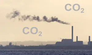 Dym z fabryki unosi się w powietrzu, a obok pojawia się napis CO2, sugerując, czy dwutlenek węgla jest cięższy od powietrza.