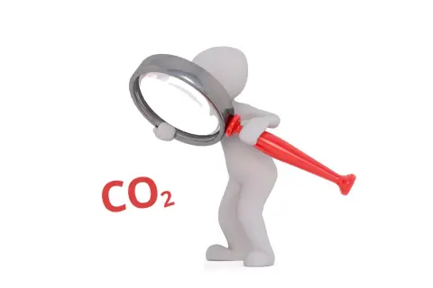 Biała figurka bada pod lupą, czy dwutlenek węgla (CO2) jest szkodliwy.