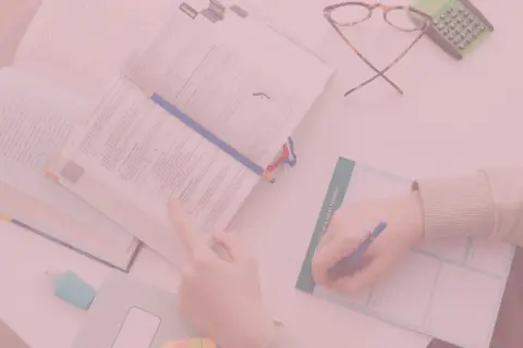 Uczeń pochyla się nad książką, notując w zeszycie. Czy oceny na studiach mają znaczenie?