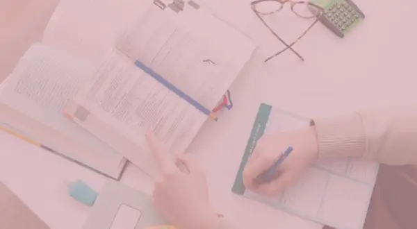 Uczeń pochyla się nad książką, notując w zeszycie. Czy oceny na studiach mają znaczenie?