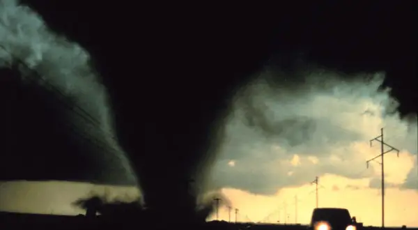 Potężny lejek tornado zbliża się do drogi, gdzie jedzie samochód. To przerażające skutki cyklonów tropikalnych.