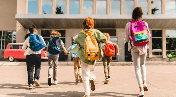 Dzieci z plecakami biegną do szkoły. Czy podstawa i program nauczania pochodzą z jednej rodziny?