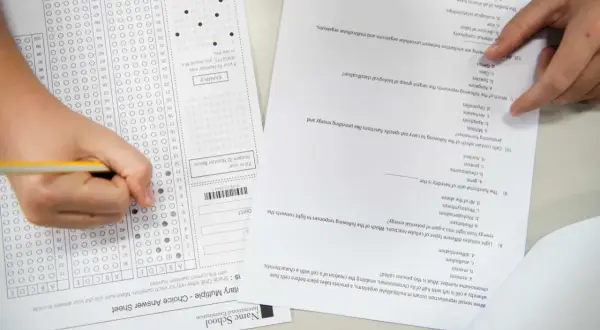 Ręka zaznacza odpowiedzi na arkuszu z biologii rozszerzonej. Zastanawiasz się, ile trwa matura z rozszerzonej biologii?