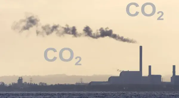 Dym z fabryki unosi się w powietrzu, a obok pojawia się napis CO2, sugerując, czy dwutlenek węgla jest cięższy od powietrza.