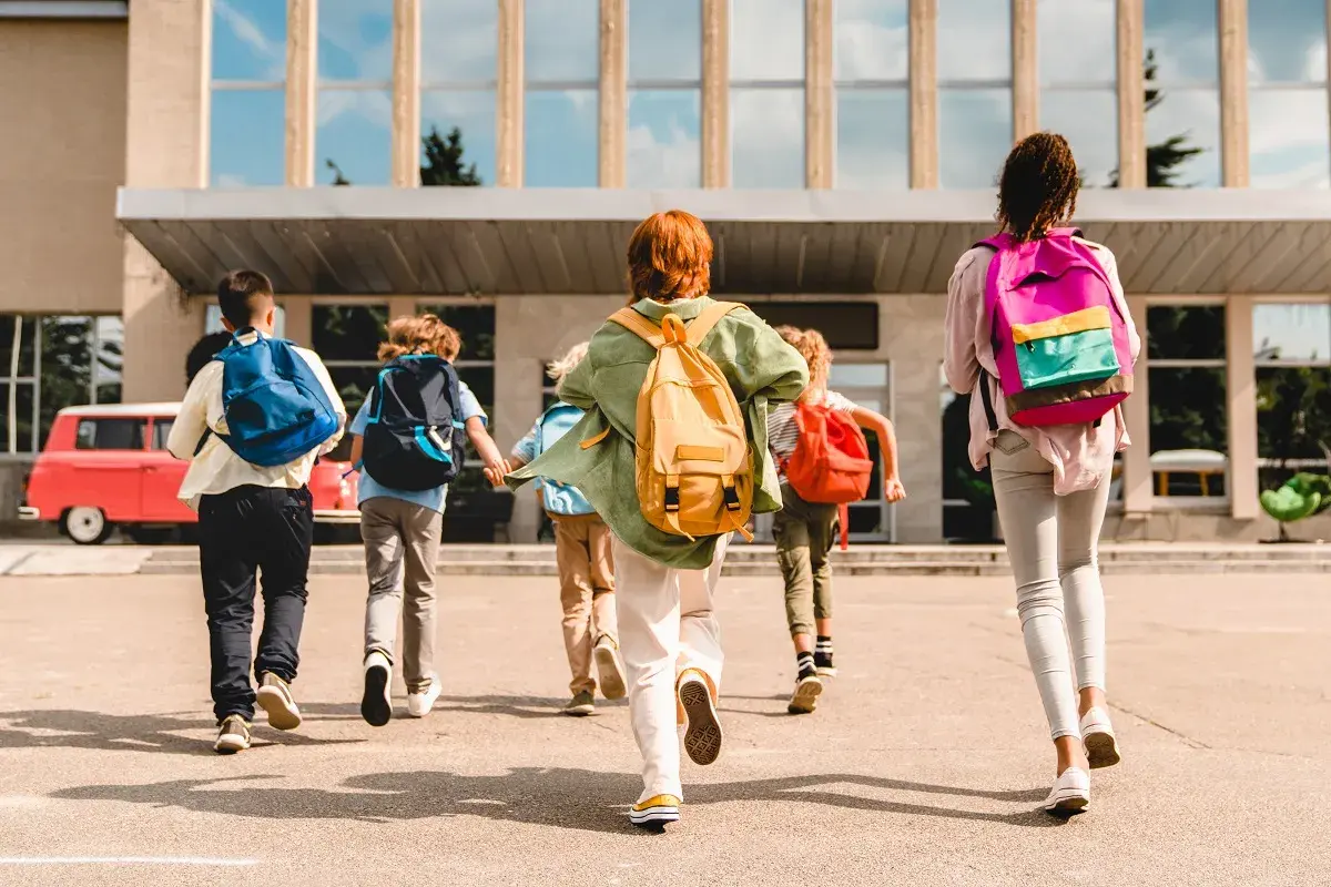 Dzieci z plecakami biegną do szkoły. Czy podstawa i program nauczania pochodzą z jednej rodziny?