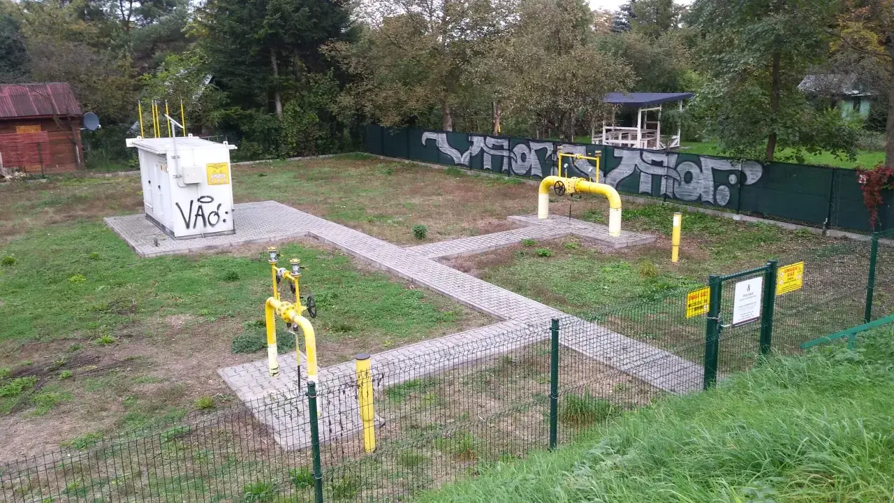 Stacja gazowa z żółtymi rurami i tabliczkami "Uwaga Gaz". Obok biała skrzynka z napisem "Vão:". To miejsce, gdzie sprawdzamy, ch4 co to za gaz.