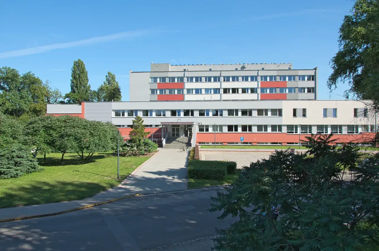Instytut Niskich Temperatur i Badań Strukturalnych PAN we Wrocławiu. Nowoczesny budynek z czerwonymi i szarymi elementami, otoczony zielenią.